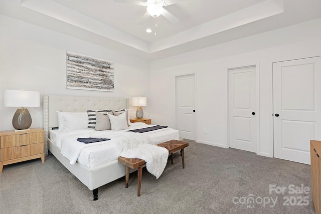 carpeted bedroom featuring a tray ceiling and ceiling fan