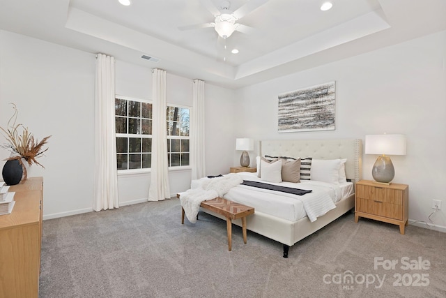 carpeted bedroom with ceiling fan and a tray ceiling