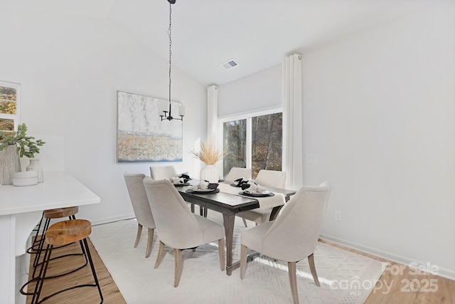 dining room featuring vaulted ceiling and light hardwood / wood-style flooring