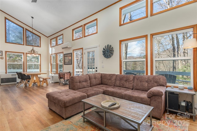 living room featuring a high ceiling, crown molding, a wall mounted AC, and light wood-type flooring