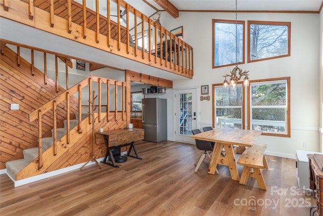 dining room with hardwood / wood-style flooring, high vaulted ceiling, beamed ceiling, and an inviting chandelier