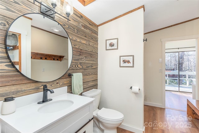 bathroom featuring toilet, vanity, ornamental molding, and wooden walls