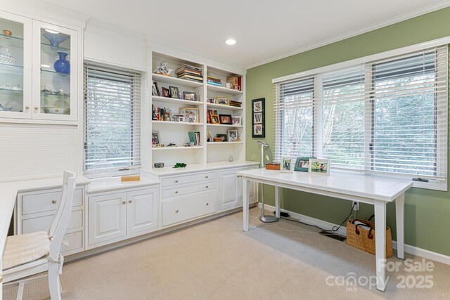 office space with plenty of natural light, baseboards, ornamental molding, and light colored carpet