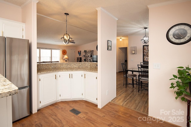 kitchen with white cabinetry, stainless steel fridge, light wood-type flooring, and pendant lighting