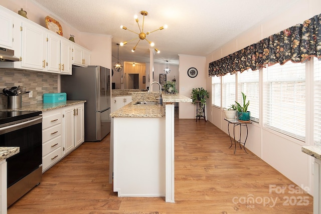 kitchen featuring sink, appliances with stainless steel finishes, light stone countertops, a textured ceiling, and white cabinets