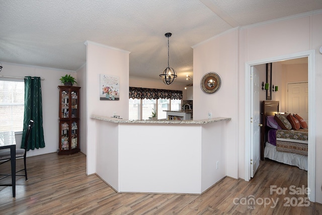 kitchen with pendant lighting, ornamental molding, a textured ceiling, and hardwood / wood-style flooring