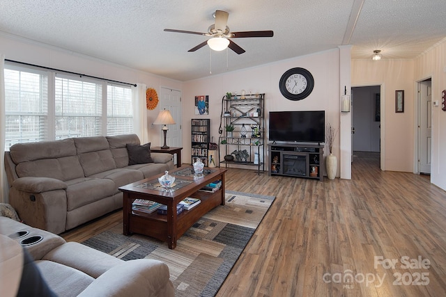 living room with crown molding, ceiling fan, hardwood / wood-style floors, and a textured ceiling