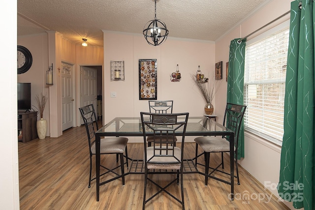 dining area featuring ornamental molding, hardwood / wood-style floors, a notable chandelier, and a textured ceiling