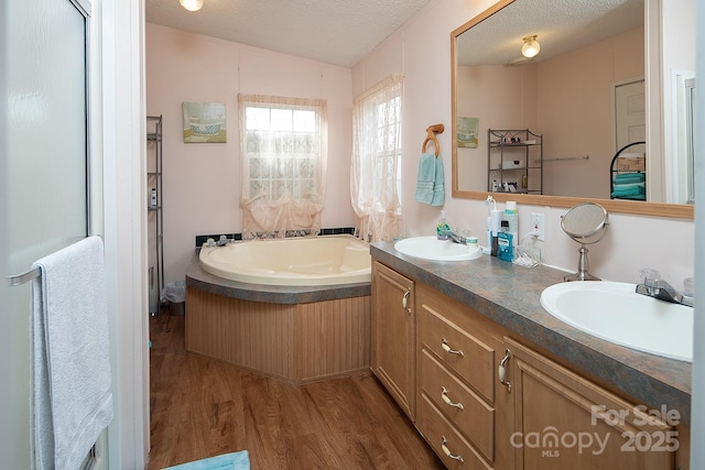 bathroom with vanity, hardwood / wood-style floors, a washtub, and a textured ceiling