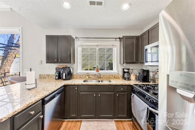 kitchen featuring light stone countertops, sink, a textured ceiling, and stainless steel appliances