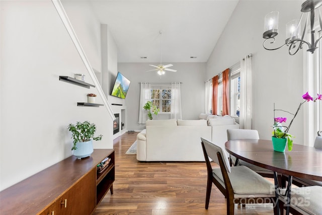 dining room with vaulted ceiling, ceiling fan with notable chandelier, and dark hardwood / wood-style floors