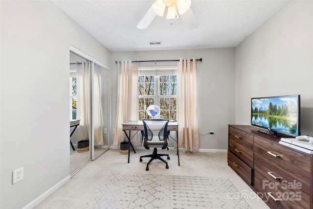 carpeted office space with ceiling fan, plenty of natural light, and a textured ceiling