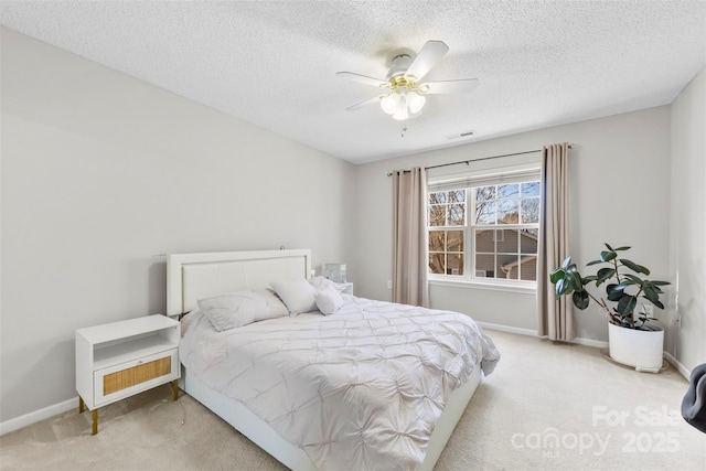 bedroom featuring a textured ceiling, light colored carpet, and ceiling fan