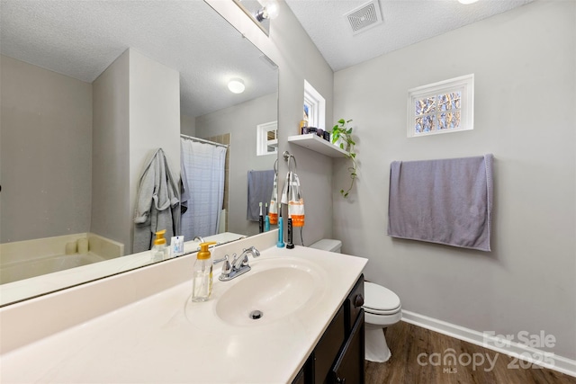 bathroom with a textured ceiling, vanity, toilet, walk in shower, and hardwood / wood-style flooring