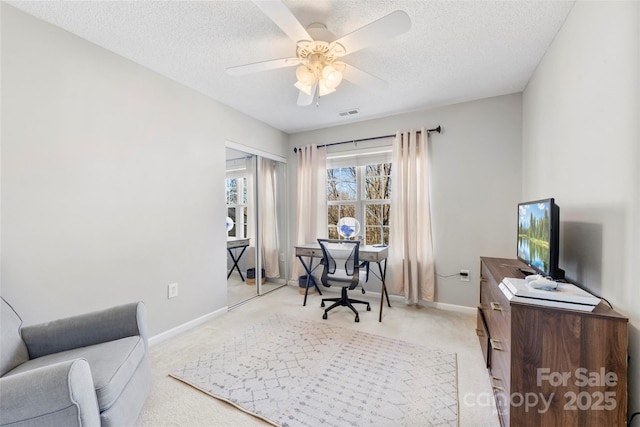 carpeted office with a textured ceiling and ceiling fan