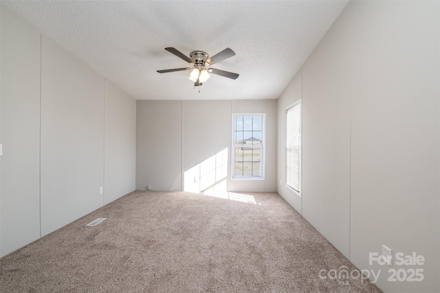 carpeted empty room with ceiling fan and a textured ceiling