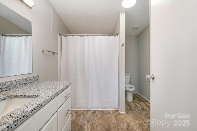 bathroom featuring a textured ceiling, toilet, and vanity