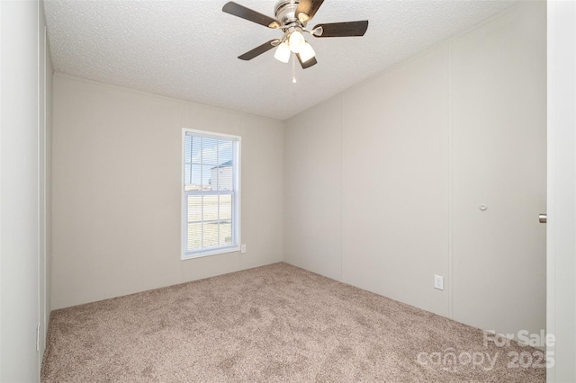 spare room with a textured ceiling, light colored carpet, and ceiling fan