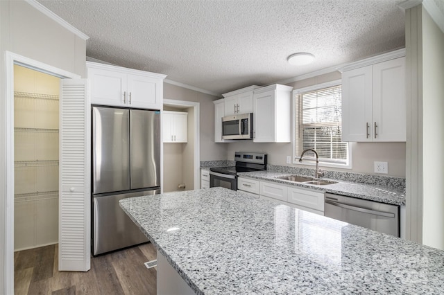 kitchen featuring appliances with stainless steel finishes, sink, white cabinets, ornamental molding, and light stone counters