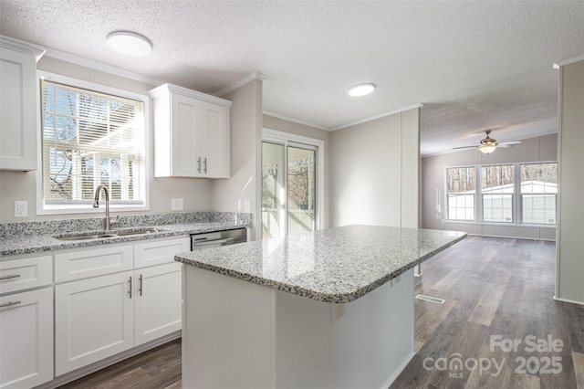 kitchen featuring sink, white cabinets, light stone counters, a textured ceiling, and a breakfast bar area