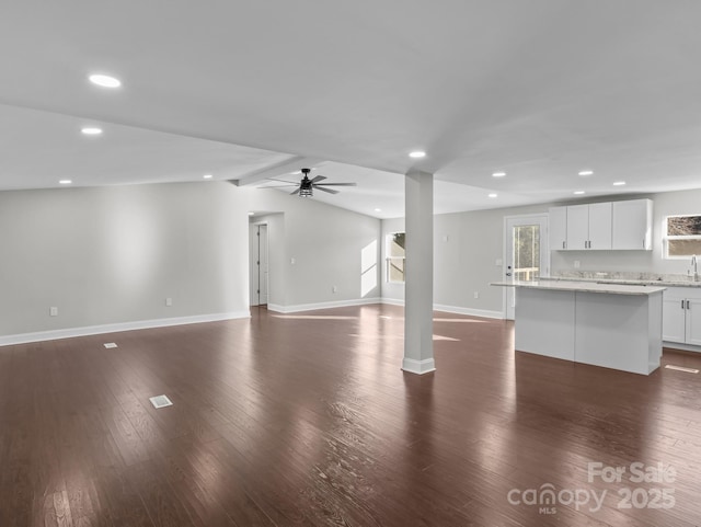 unfurnished living room featuring ceiling fan, vaulted ceiling with beams, and dark hardwood / wood-style floors