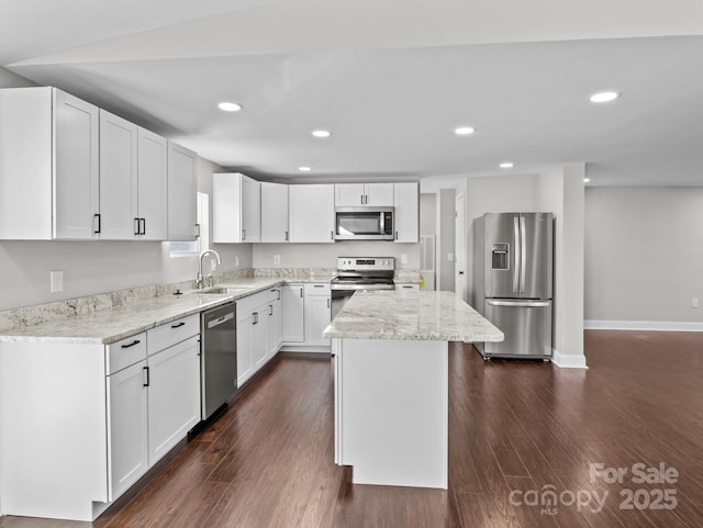 kitchen with white cabinetry, sink, a kitchen island, stainless steel appliances, and dark hardwood / wood-style floors