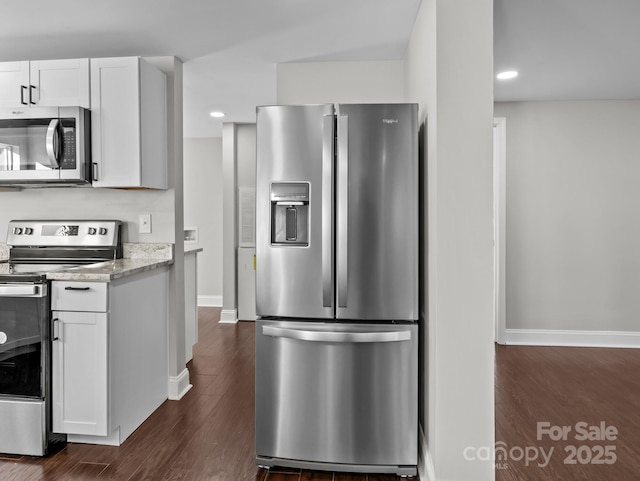 kitchen with light stone countertops, dark wood-type flooring, white cabinets, and stainless steel appliances