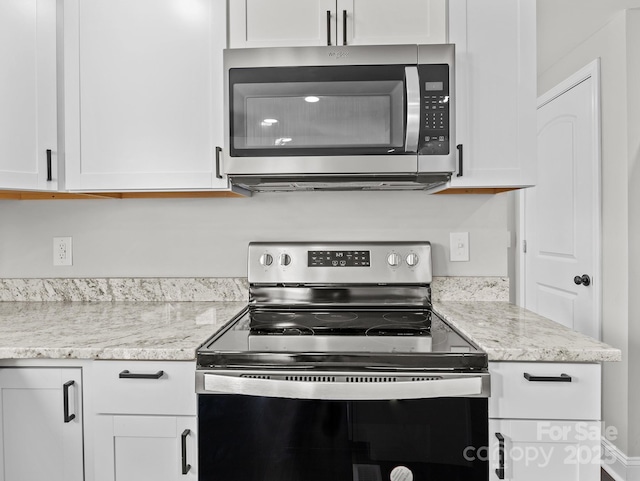 kitchen featuring light stone counters, white cabinets, and stainless steel appliances