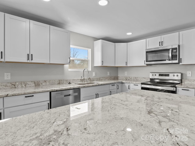 kitchen featuring sink, light stone counters, white cabinets, and appliances with stainless steel finishes