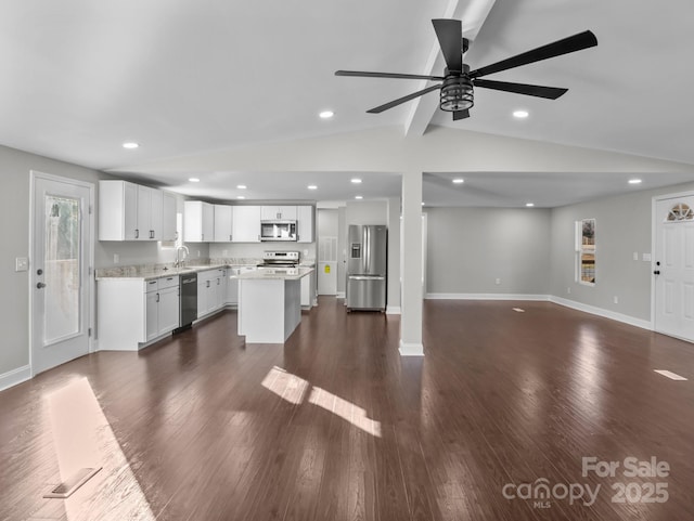 kitchen with appliances with stainless steel finishes, a kitchen island, dark wood-type flooring, white cabinetry, and vaulted ceiling with beams