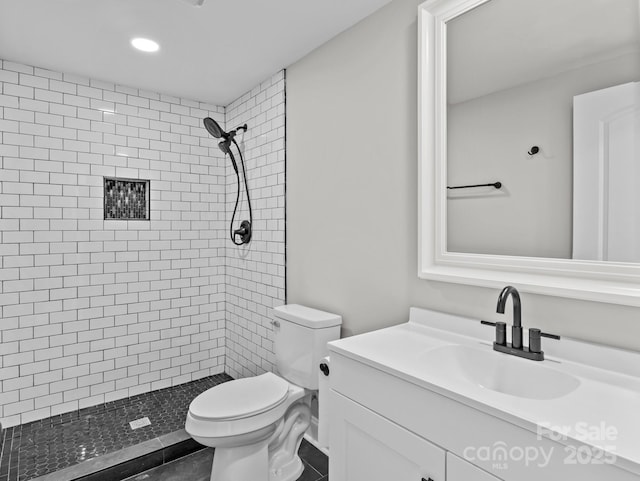 bathroom with vanity, toilet, and a tile shower