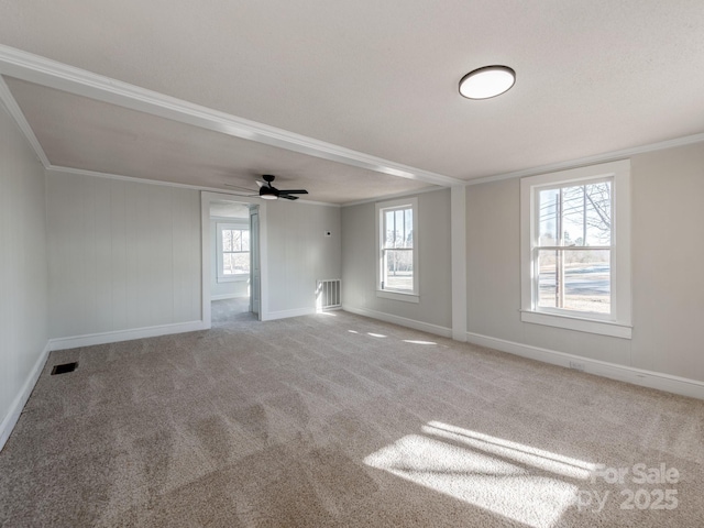 carpeted spare room with ceiling fan, a wealth of natural light, and crown molding