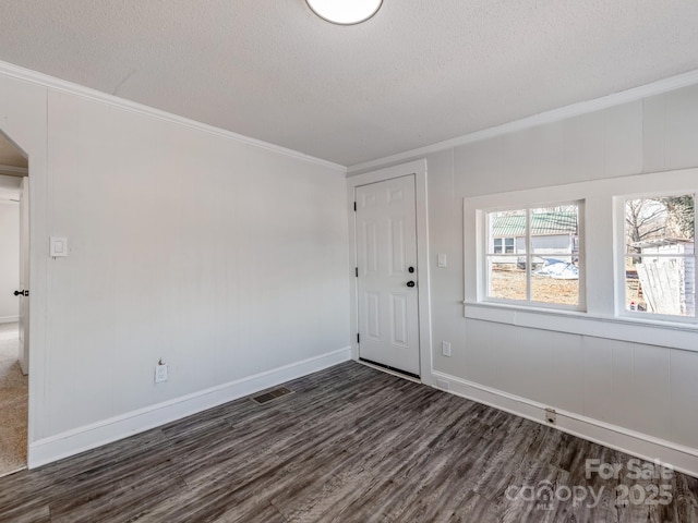 spare room featuring crown molding, dark hardwood / wood-style flooring, and a textured ceiling