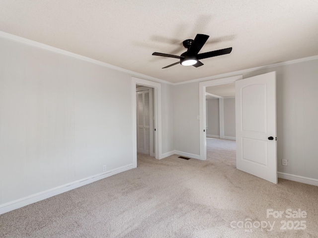 empty room featuring ceiling fan, light colored carpet, and ornamental molding