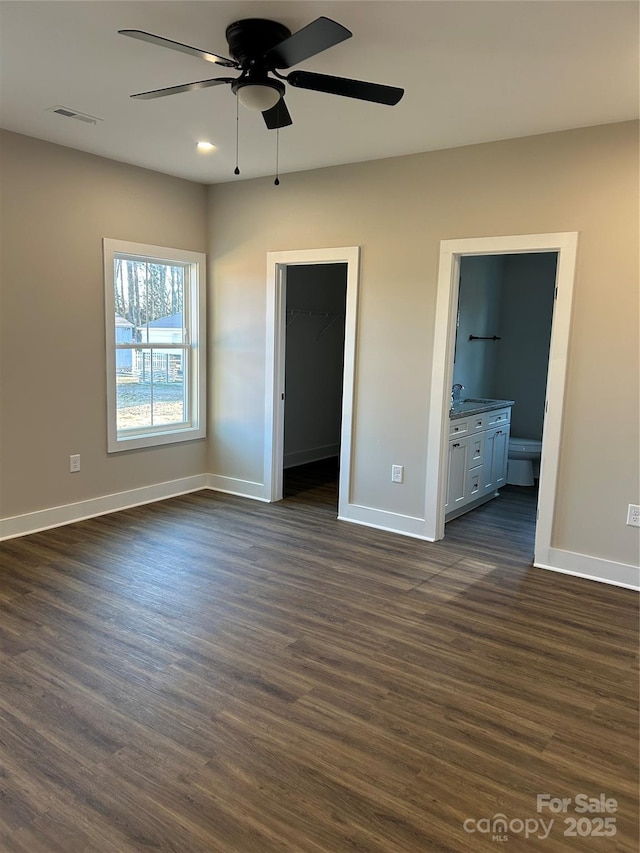 unfurnished bedroom featuring a spacious closet, ensuite bathroom, ceiling fan, a closet, and dark hardwood / wood-style flooring