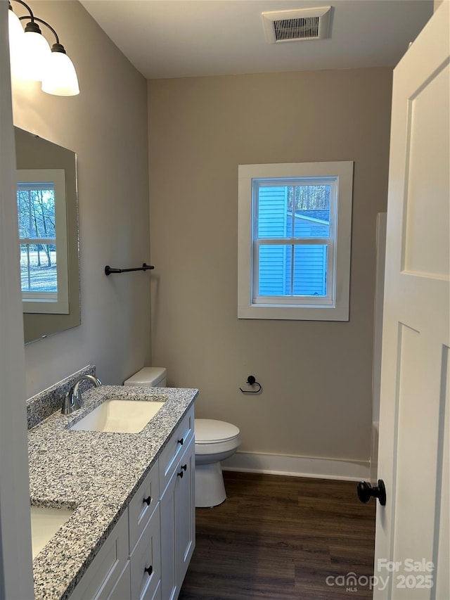 bathroom with toilet, vanity, a wealth of natural light, and hardwood / wood-style floors