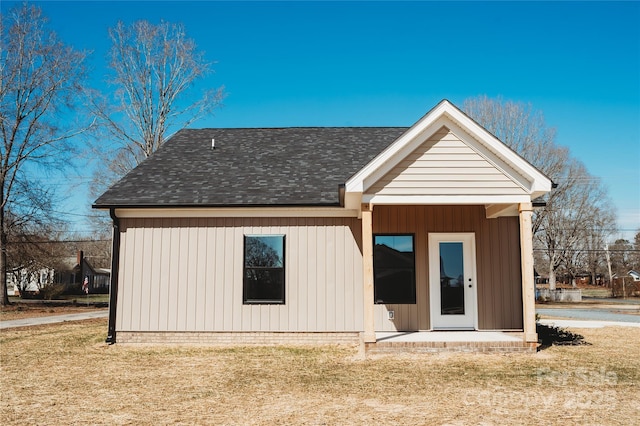 back of house featuring a yard and a shingled roof