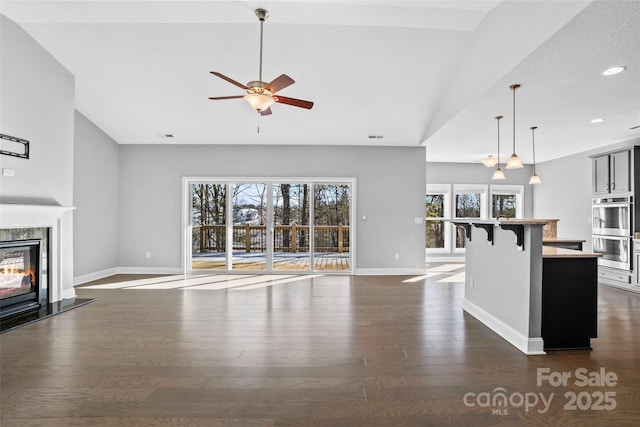 unfurnished living room featuring lofted ceiling, ceiling fan, a high end fireplace, and dark hardwood / wood-style floors