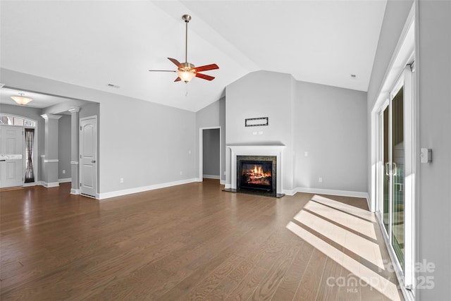 unfurnished living room with ceiling fan, vaulted ceiling, a fireplace, dark hardwood / wood-style flooring, and decorative columns