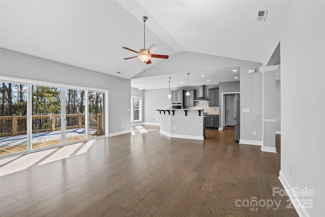 unfurnished living room with ceiling fan, vaulted ceiling, and dark hardwood / wood-style flooring