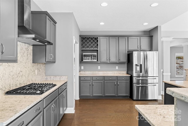 kitchen with gray cabinets, stainless steel fridge, gas cooktop, and wall chimney range hood