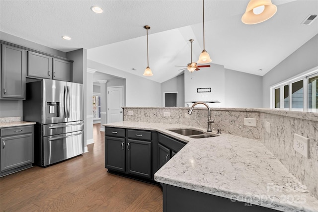 kitchen with stainless steel refrigerator with ice dispenser, decorative backsplash, gray cabinetry, lofted ceiling, and sink