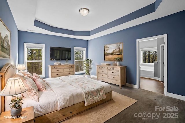 bedroom featuring a tray ceiling and dark colored carpet