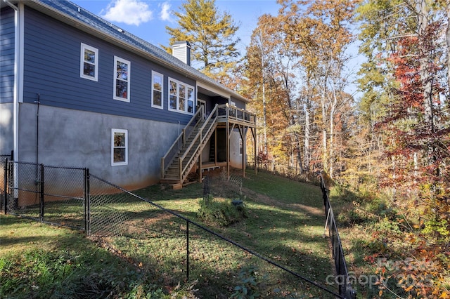 back of property with a deck and a yard