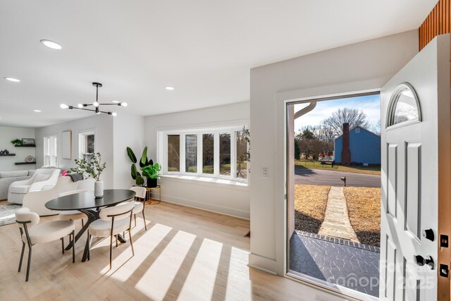 dining space featuring plenty of natural light, a notable chandelier, and light hardwood / wood-style flooring