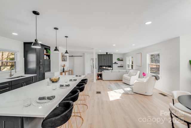 kitchen featuring sink, a center island, light hardwood / wood-style floors, a kitchen bar, and decorative light fixtures