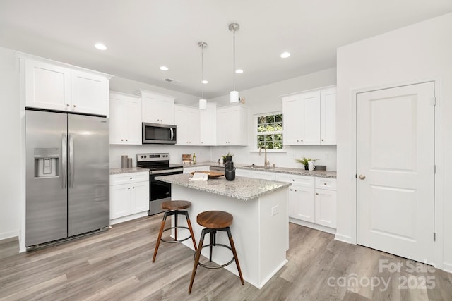 kitchen featuring white cabinetry, pendant lighting, appliances with stainless steel finishes, and a center island