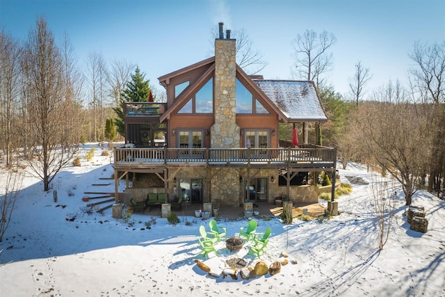 snow covered property with a wooden deck, a fire pit, and french doors