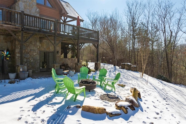 snowy yard with a deck and an outdoor fire pit