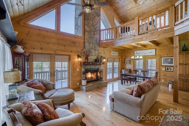 living room featuring high vaulted ceiling, light hardwood / wood-style flooring, french doors, and a fireplace